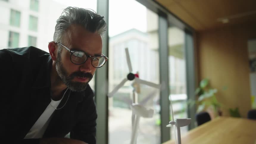 Man interacting with a wind power prototype while standing on an office desk
