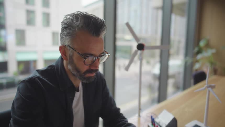 A man puts on his glasses and types on the laptop