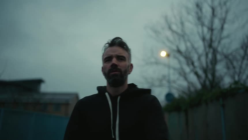 Man standing outdoors at dusk and stretching his arms