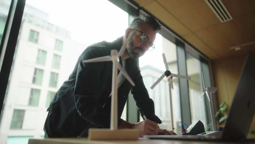 A man is writing and working in the office