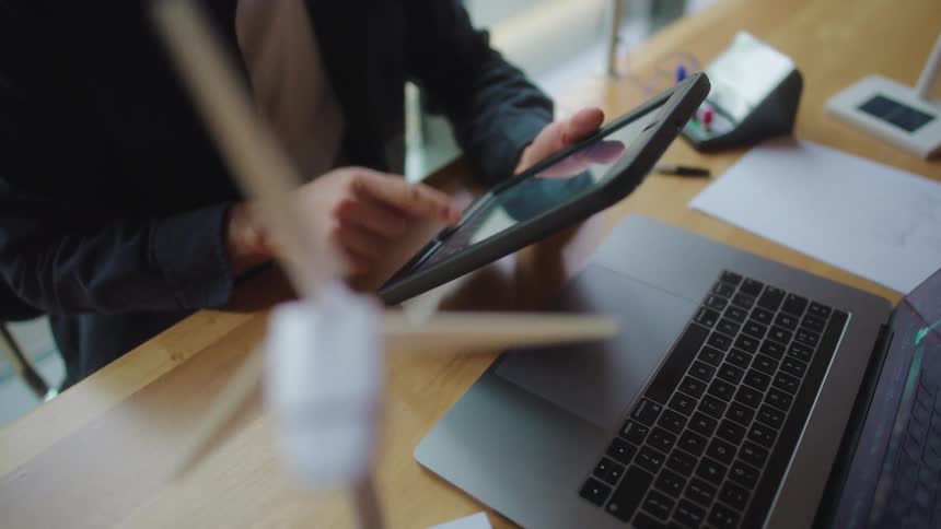 A man is typing on his tablet at the desk