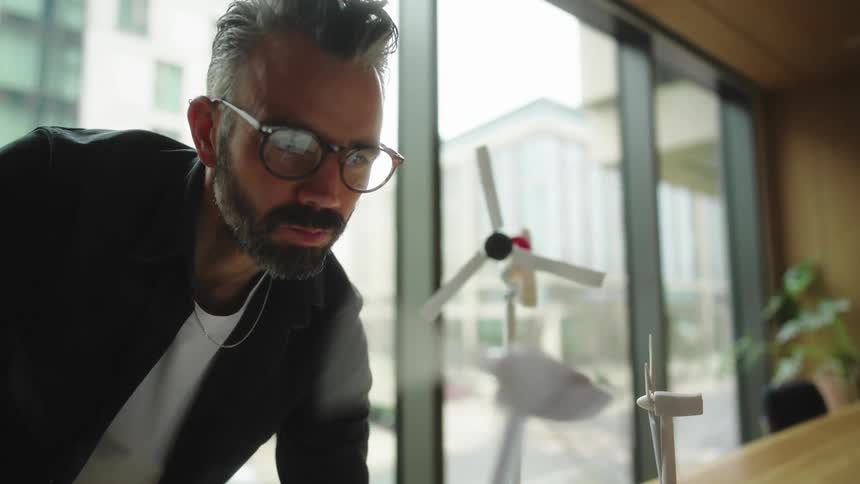 A man spins the blades on a model windmill