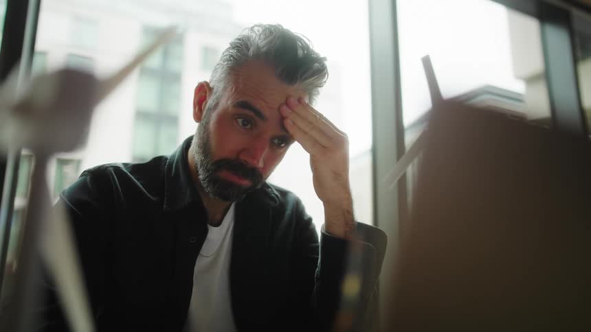 Thoughtful man touches his face and puts on his glasses