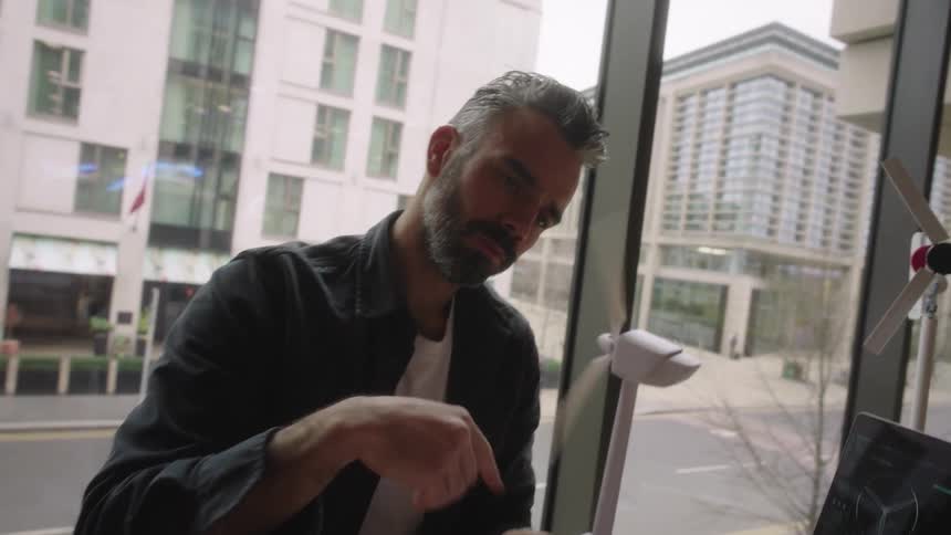 A man is examining a windmill model and writes some notes