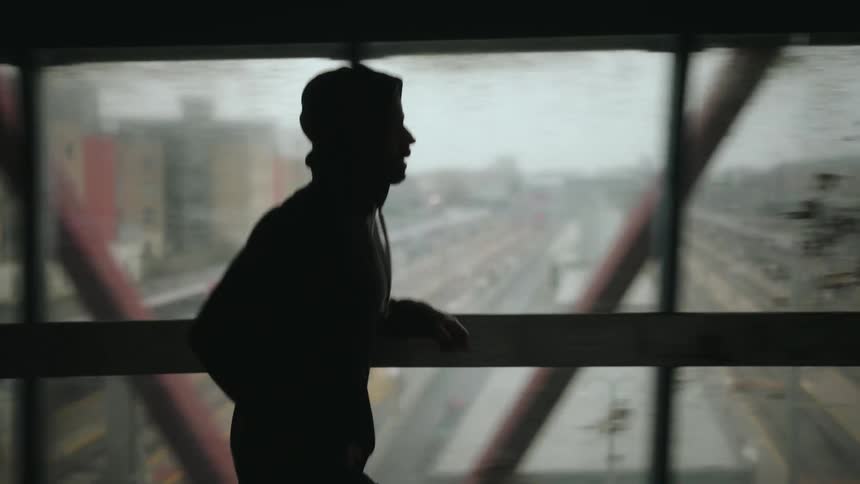 Person wearing a cap running in an indoor space on an overpass