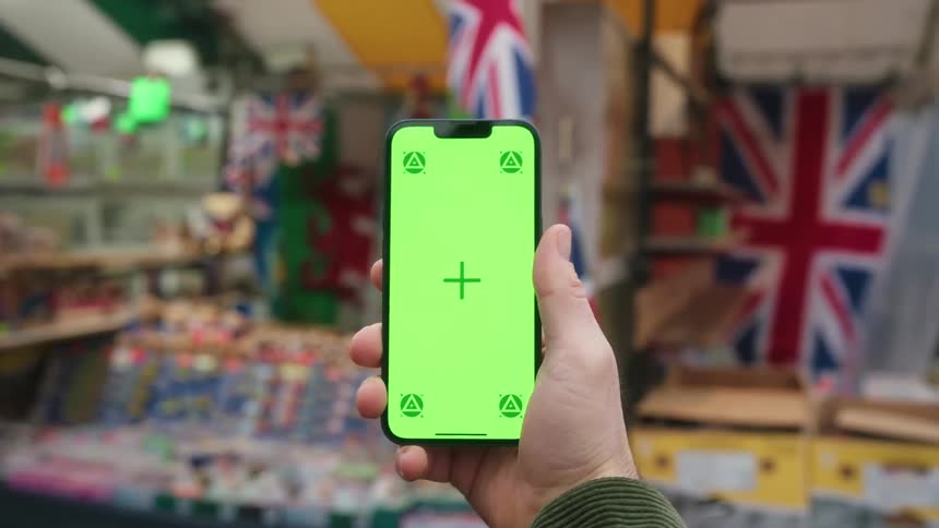 Person holding a smartphone in front of a market stall