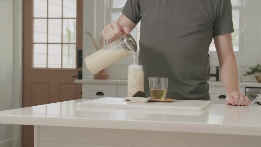 Pair of hands preparing a cold drink by pouring the milk