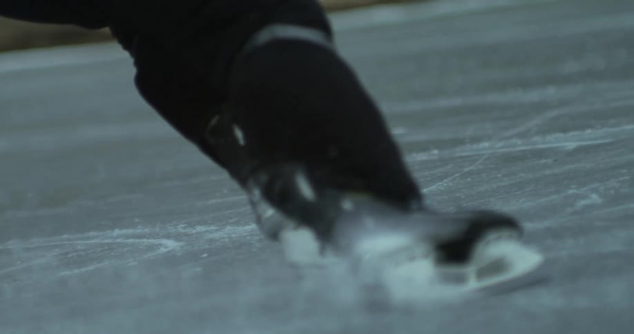 Hockey player skates across an outdoor ice rink on a winter day