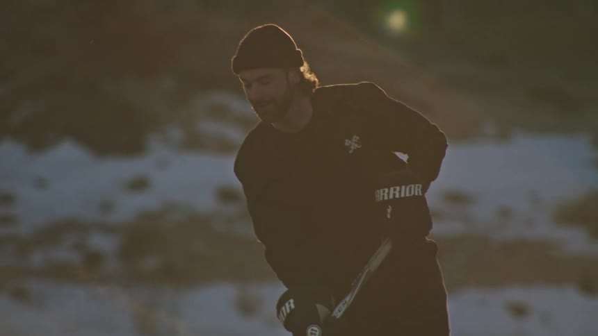 A hockey player skates and handles the puck on an outdoor rink his breath visible in the cold air