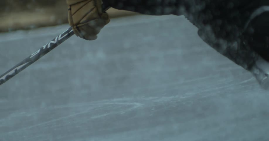 Person with hockey stick sliding down an ice rink