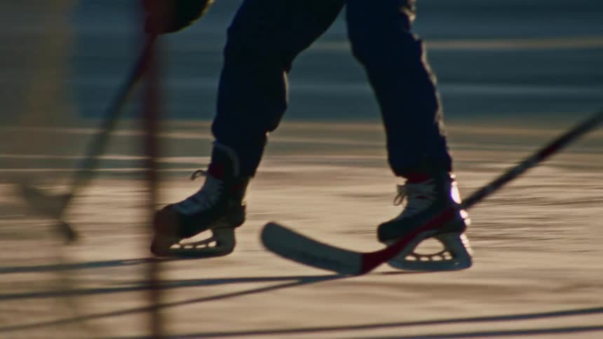Two men playing a game of hockey in the late afternoon