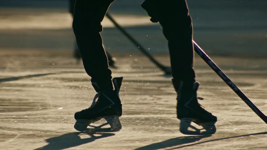 A person playing hockey on an ice rink and using bladed shoes to glide over the icy surface