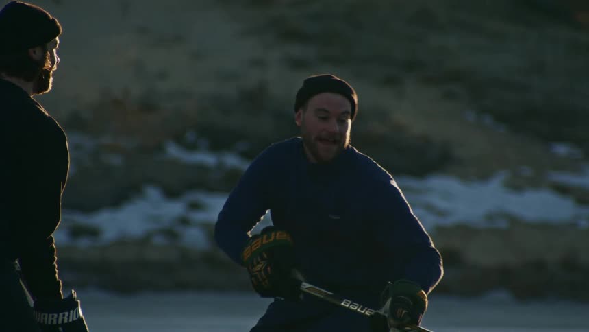 Two people in warm clothes playing hockey and are happy in freezing cold environment