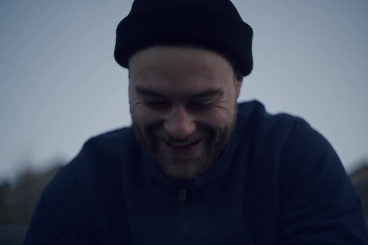 A man is smiling and laughing outside