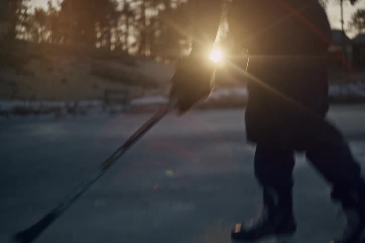 Man practices hockey at an ice rink near his rural home near sunset