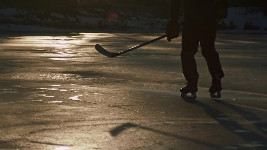 A man is chasing after the puck while playing hockey on ice