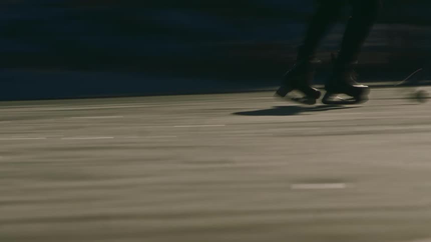 Skater glides quickly across the ice casting an elongated shadow