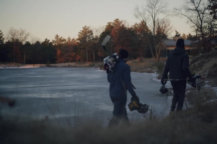 Two people walking next to an ice rink with hockey equipment