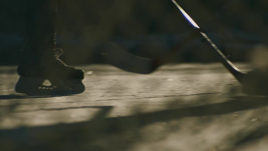 People in ice skates skating over a frozen lake playing hockey in the morning