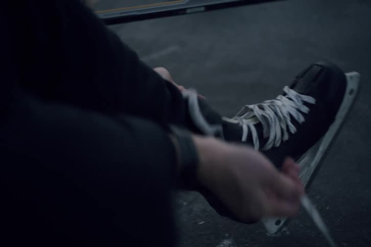 Person adjusts the laces of an ice skate before entering the rink