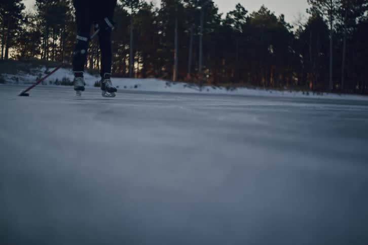 Person showing skills with a hockey stick on an ice rink with trees in the background