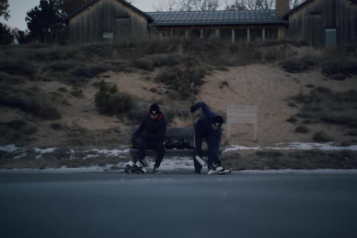 Two men sit down and put on hockey equipment