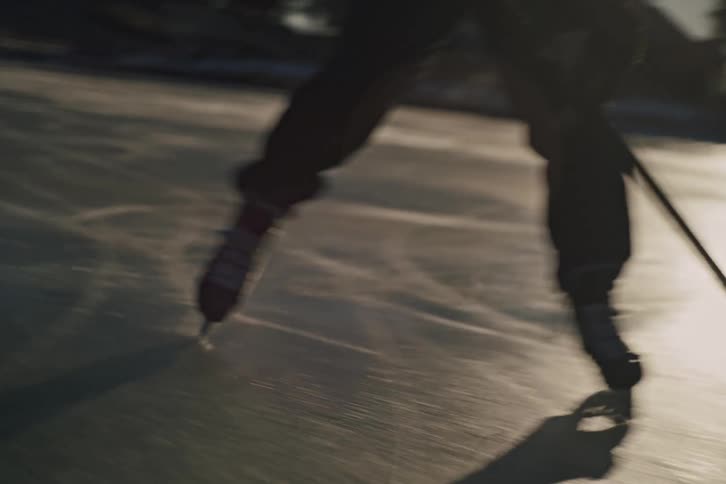 A hockey player skates and stickhandles a puck on an outdoor rink