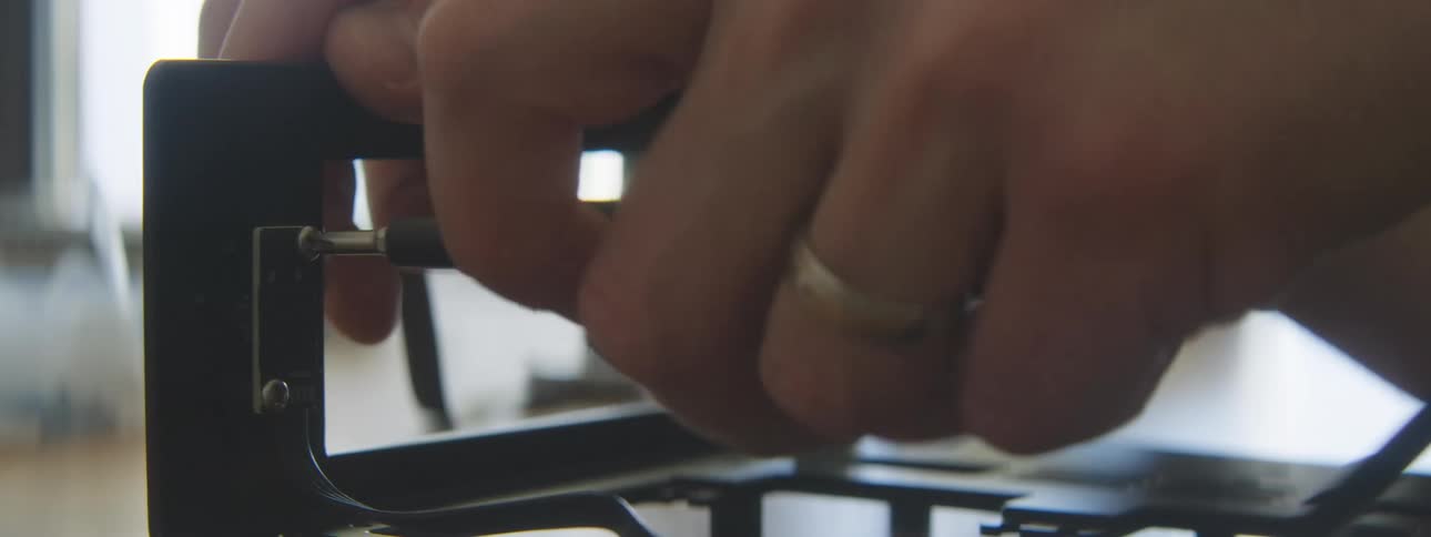 A person screws a small screw in