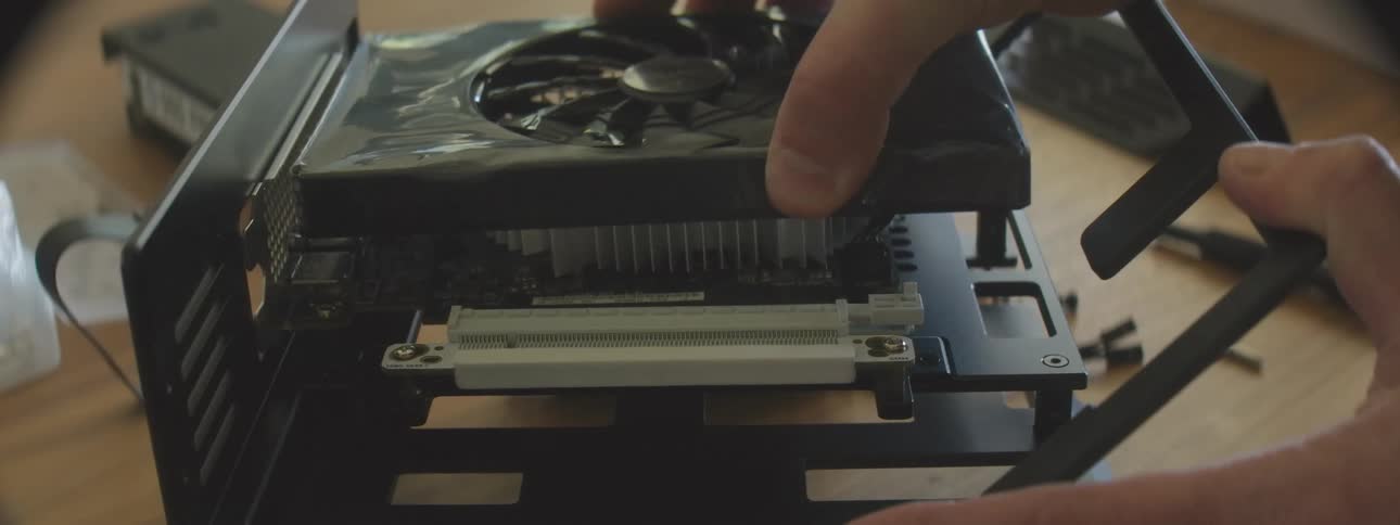 A person plugs a graphic card into the computer