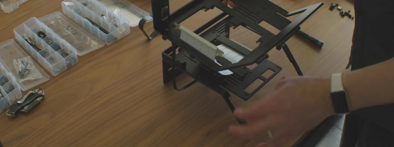 Person assembling a computer case on a table with parts and tool organizers