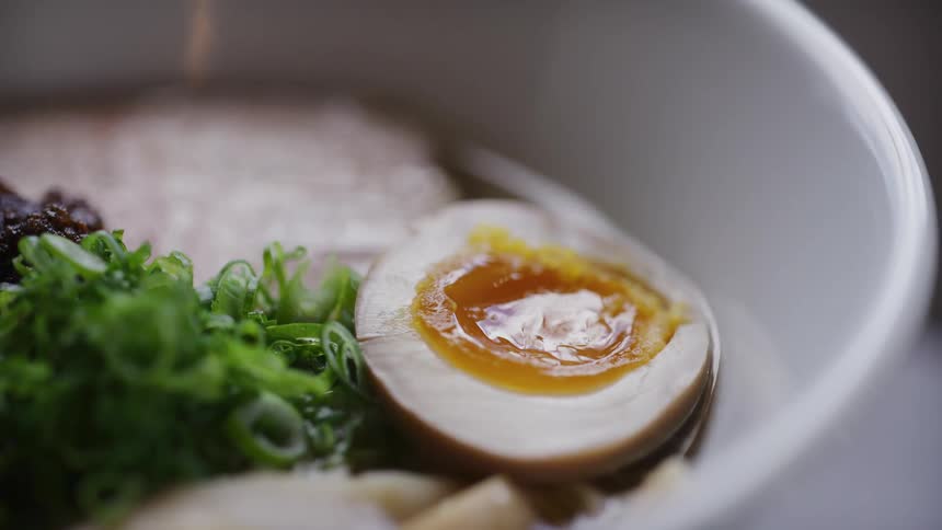Close up of a white bowl with ramen in sauce