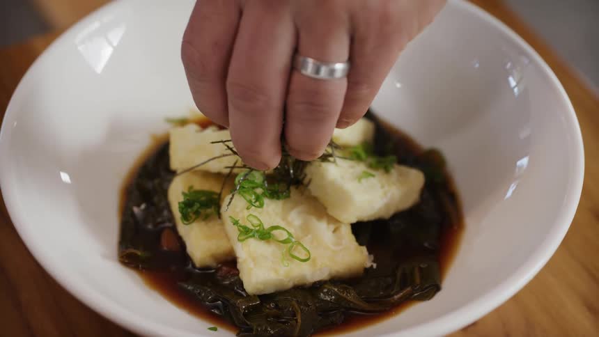 Dish with fried tofu on seaweed in soy sauce finished with chopped chives