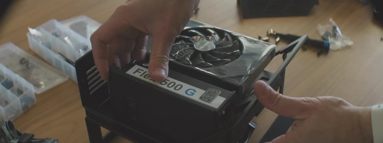 Person assembles a computer by installing a power supply and a video card