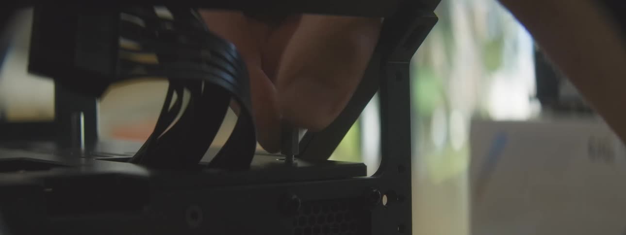A closeup shot shows a hand adjusting a small silver knob on a metal computer frame