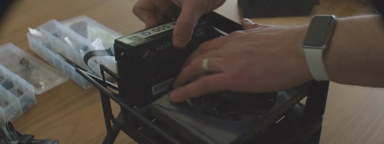 Person installs a power supply in an open case on the table