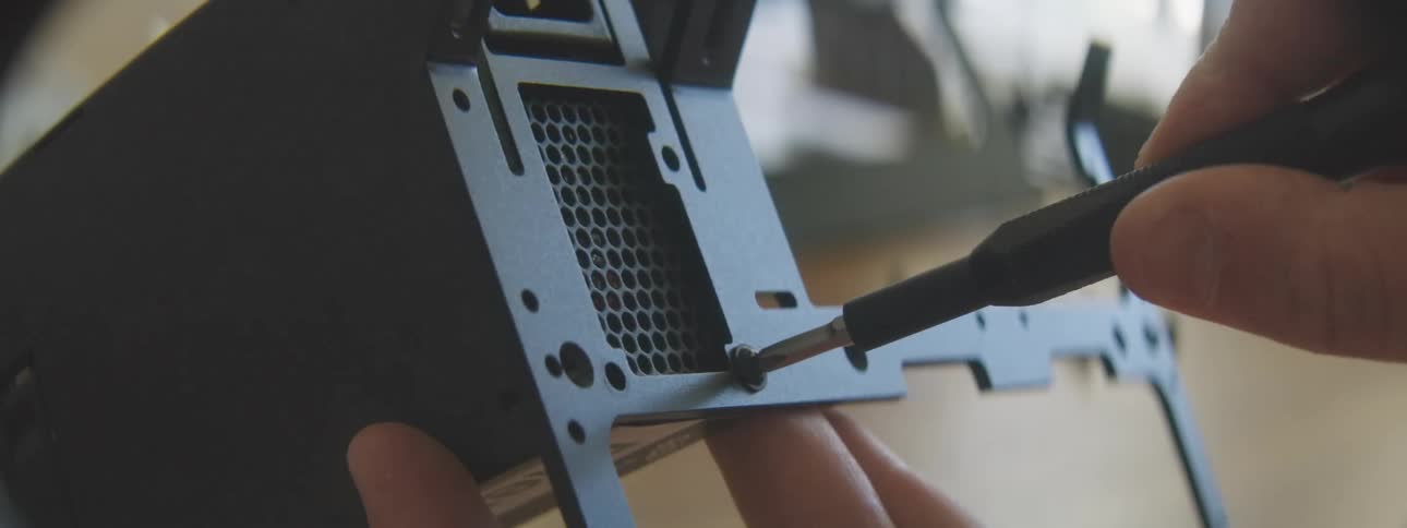 A person is putting screws in the computer case as they build
