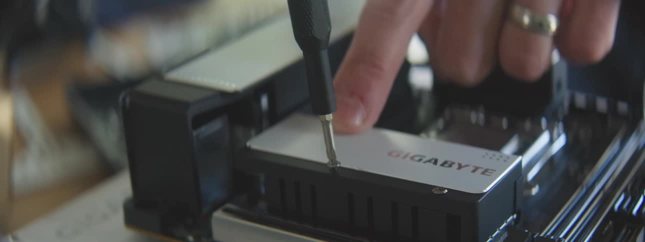 Hands installing a gigabyte ssd into a computer motherboard
