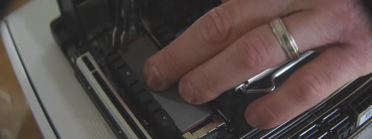 A closeup shot shows a hand adjusting an sd hard drive onto a computer motherboard