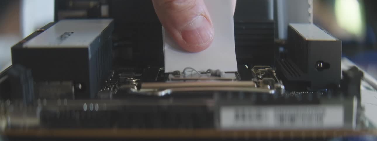 Hand putting thermal paste on a motherboard and then wiping off the excess