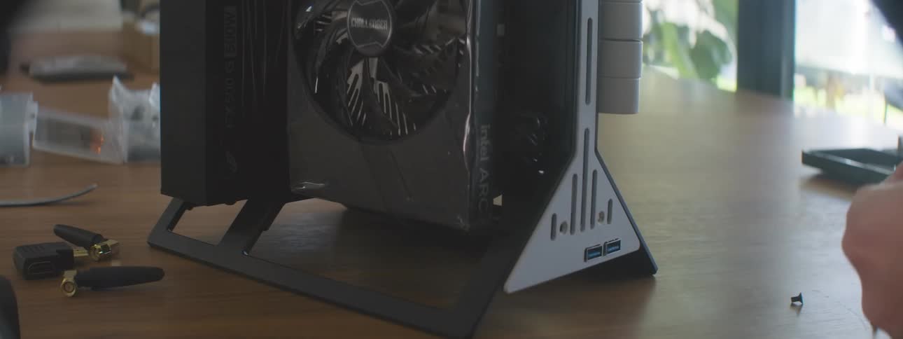 Person uses a tool to adjust the frame of an open computer case on a table