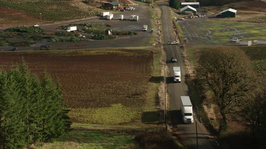 A rural street with two white trucks passing by seen from above