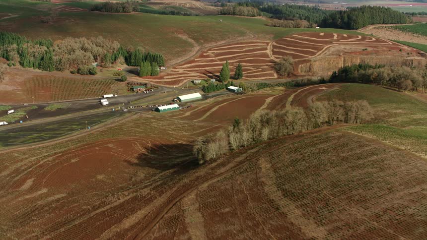 An aerial shot shows a vast landscape of rolling hills with cultivated fields and farms