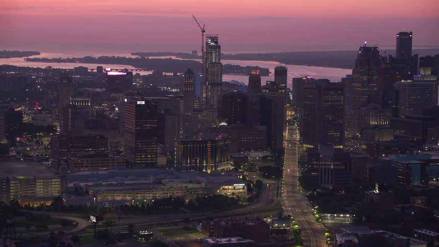 Aerial view of a city illuminated at dusk with skyscrapers and a river in the background