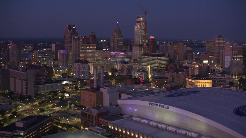 An aerial night view of the detroit skyline featuring ford field prominently with illuminated highways buildings and a dark sky