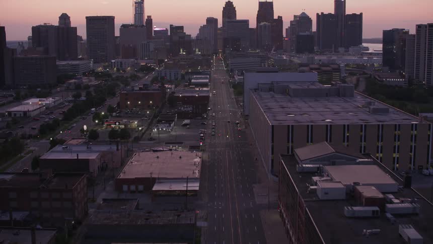 Aerial view of a city at dusk with a long avenue illuminated by urban lights