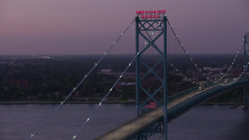Ambassador bridge illuminated at dusk with the city in the background