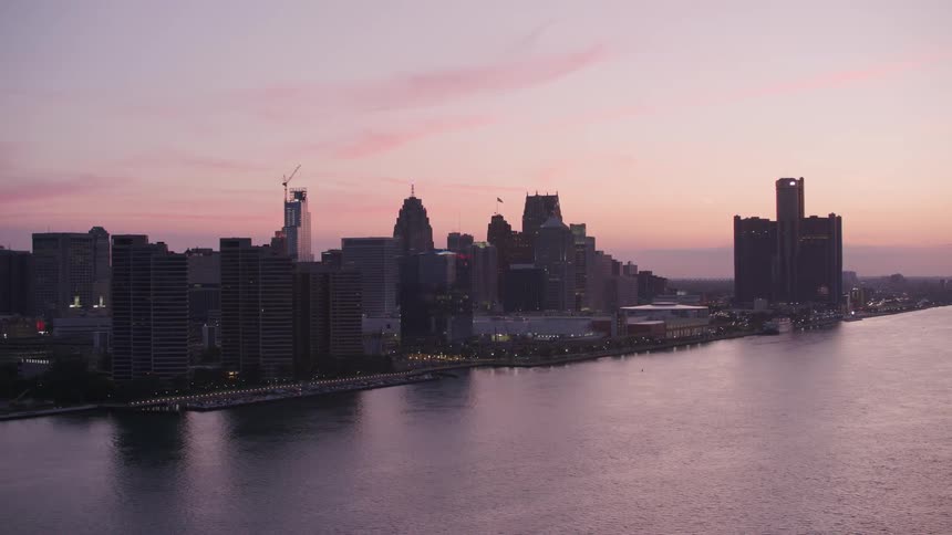 Riverside city illuminated by sunset with pink sky