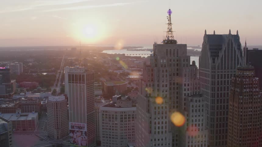 An aerial view of a metropolitan city with skyscrapers and a flare of sunlight coming from the sky