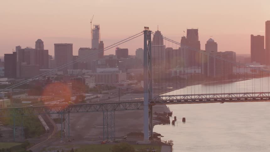 Aerial view of a long bridge with skyscrapers and the red sun on the horizon