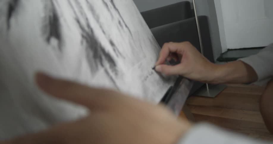 An artist signs their name to a drawing